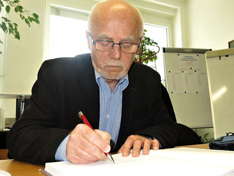 Jiřà Brýdl se zapisuje do pamětnà klnihy školy.